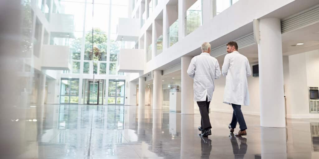 Dois médicos caminhando por uma clínica moderna e iluminada, simbolizando o acolhimento e a ética no processo de barriga solidária no Brasil.