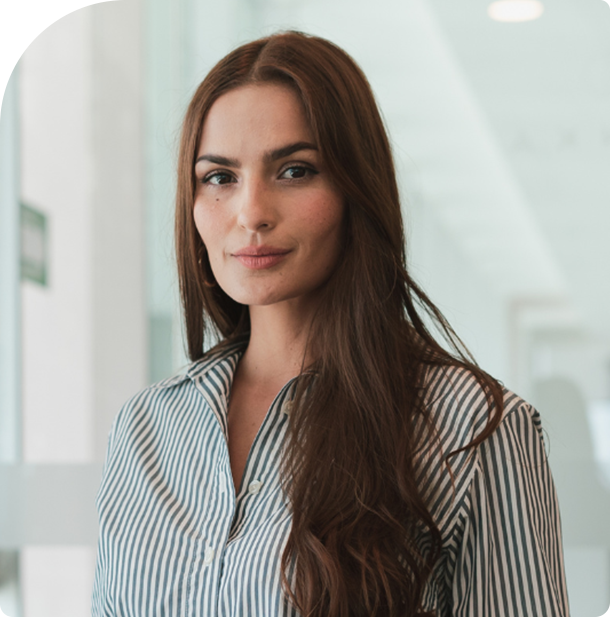 Mulher confiante e profissional, com expressão serena, usando camisa listrada em ambiente clínico moderno.
