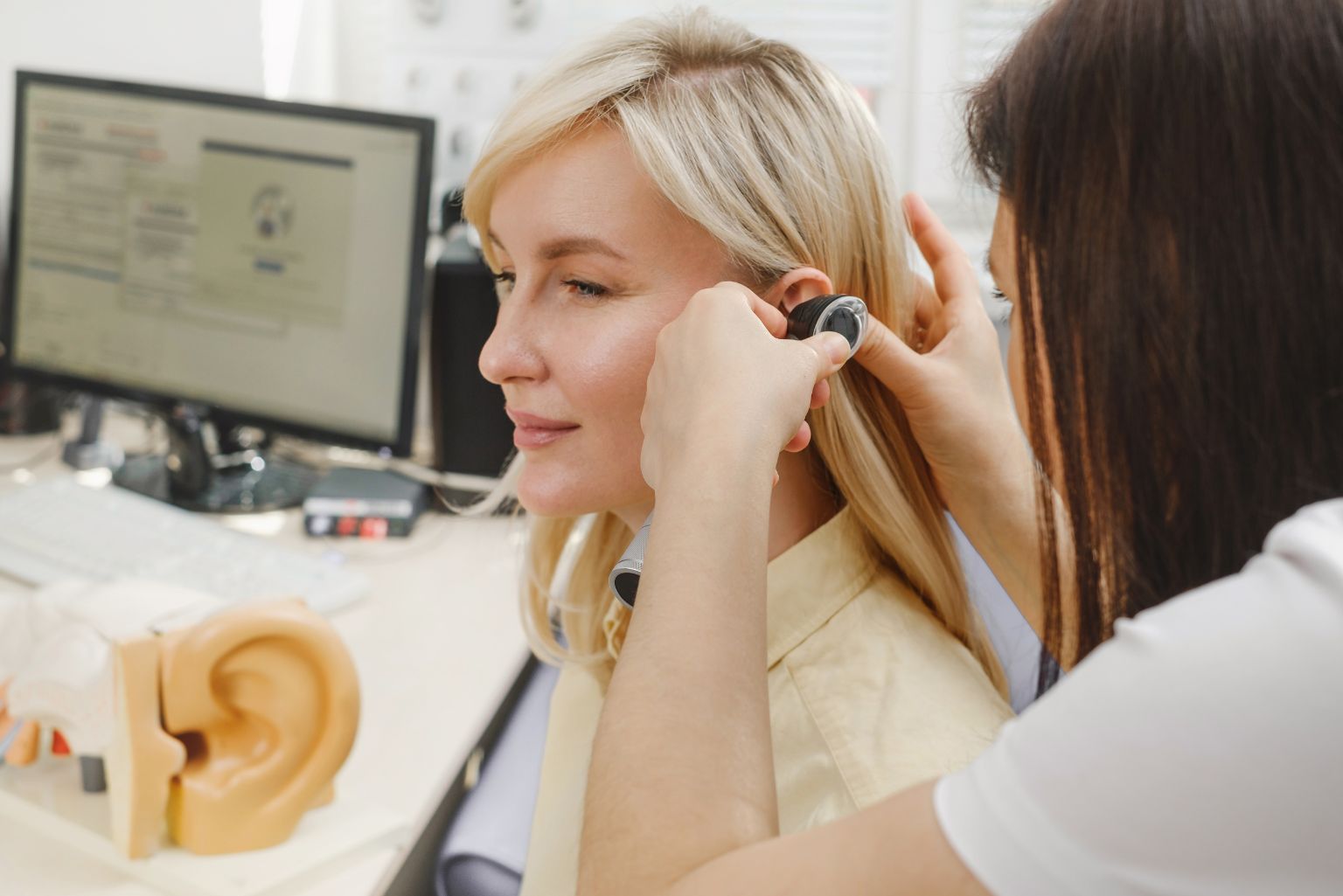 Médica realiza exame de ouvido em paciente, em avaliação de sintomas relacionados à otosclerose.