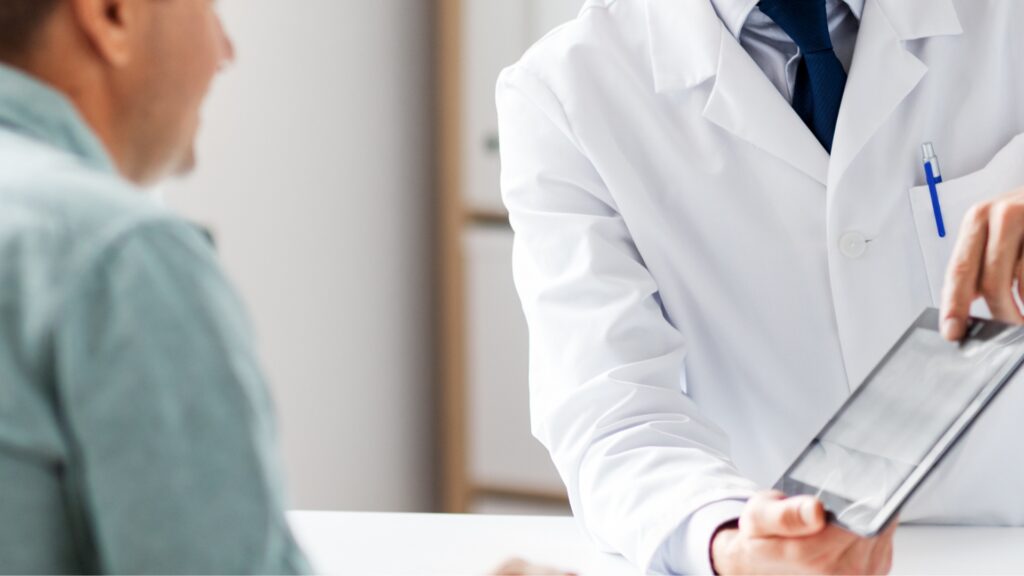 Médico orientando paciente masculino durante consulta sobre infertilidade masculina, diagnóstico e opções de tratamento.