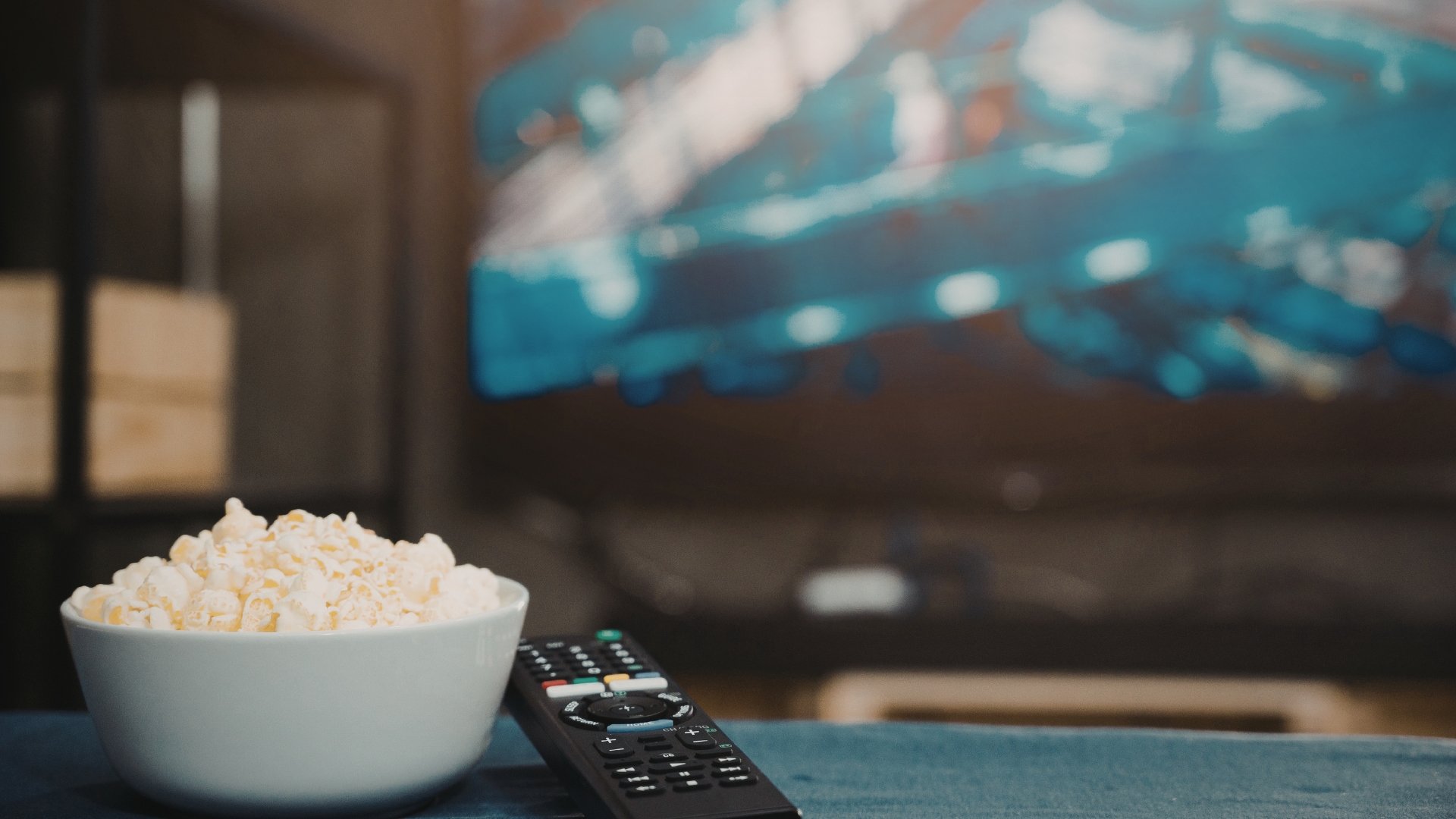 Tigela de pipoca e controle remoto em frente à televisão, representando um momento de descanso e lazer para grávidas em casa