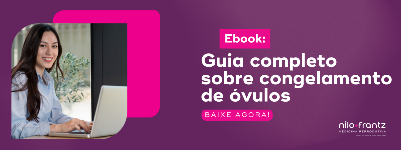 Mulher sorrindo em frente ao notebook com banner de ebook sobre congelamento de óvulos da Nilo Frantz.