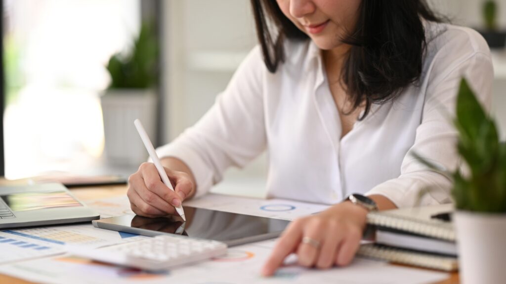 Mulher utilizando tablet e analisando documentos financeiros relacionados ao custo do congelamento de óvulos e planejamento de carreira.