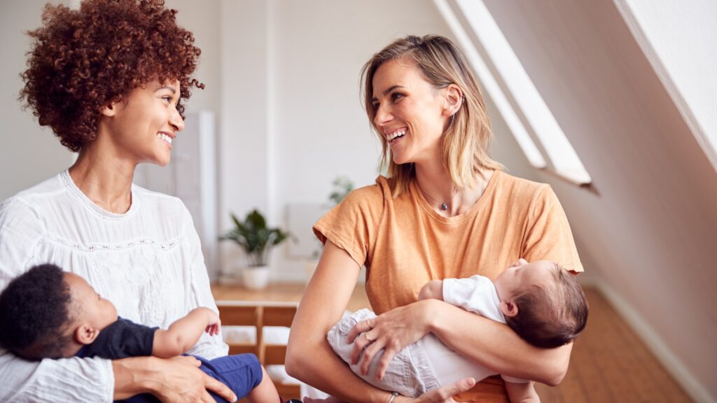 Duas mães conversando enquanto seguram seus bebês, representando histórias reais e experiências de ovodoação.