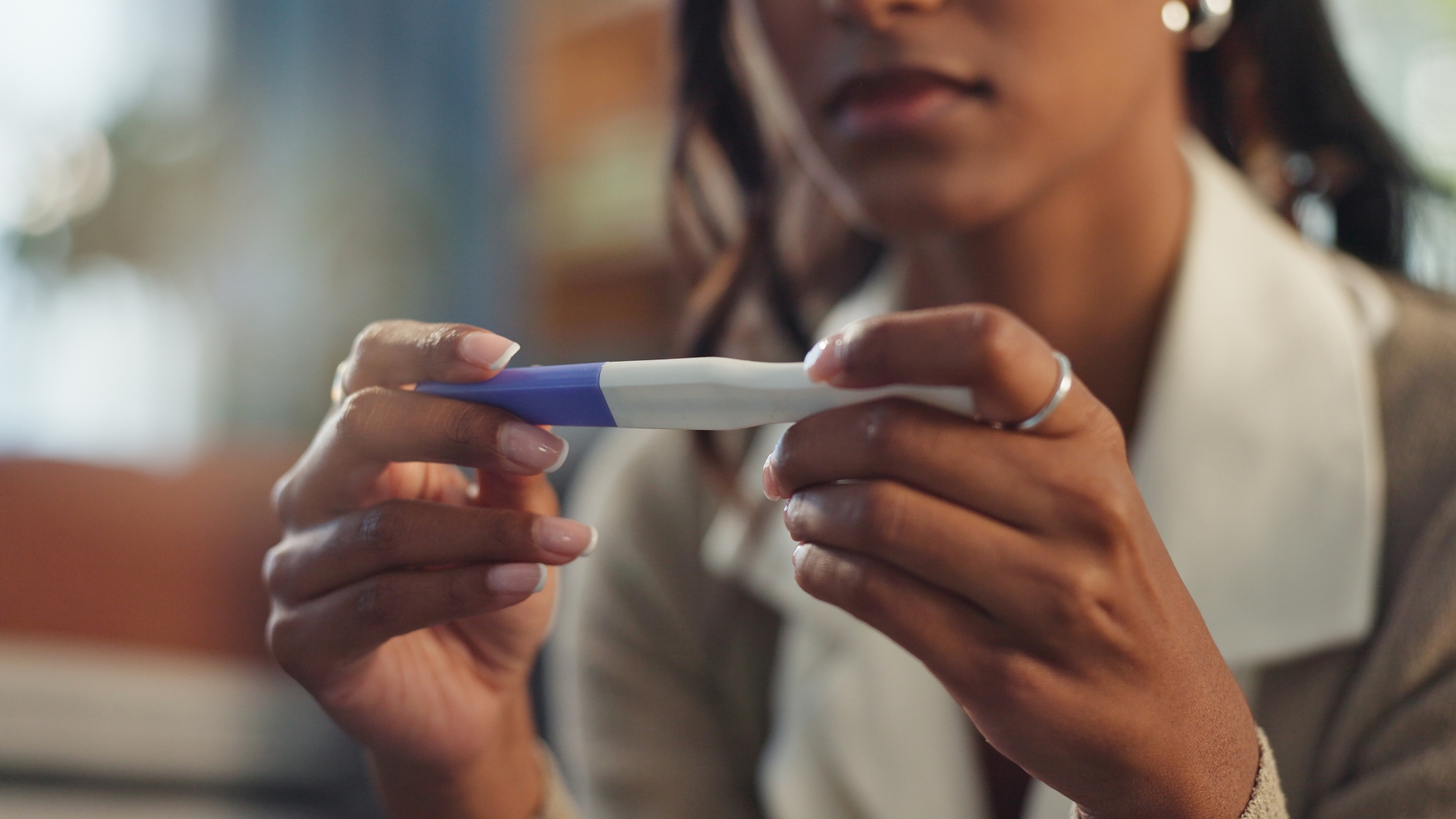 Mulher elegante segurando um teste de gravidez, representando emoções e decisões relacionadas à ovodoação e fertilidade.